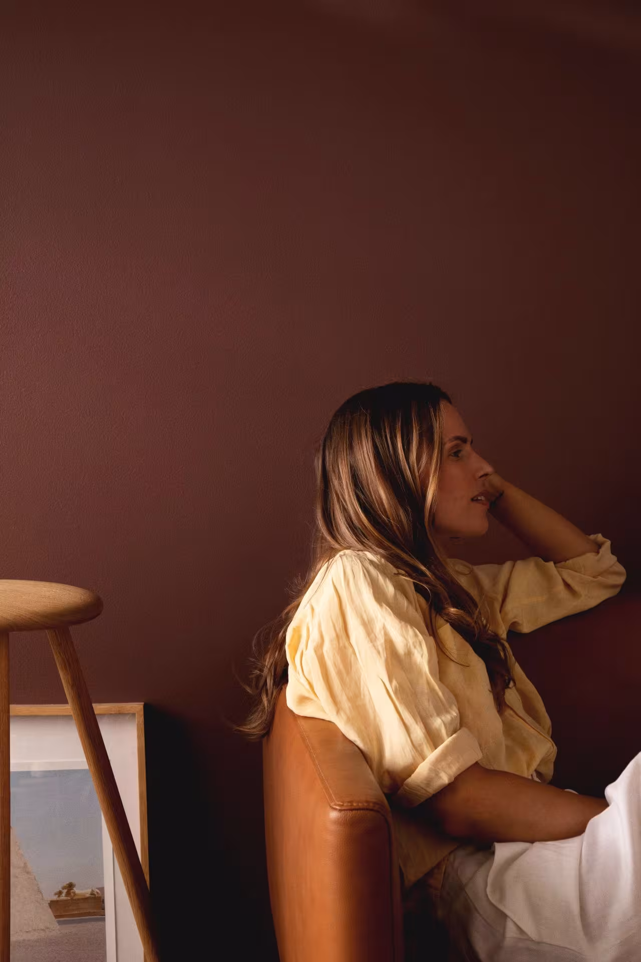 woman sitting on sofa in front of warm brown colour wall